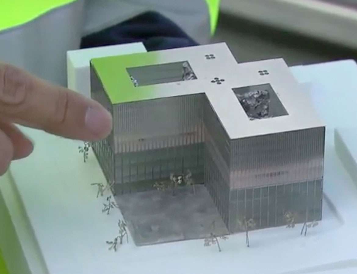 Photo shows a dinger pointing to a scale model of the Rechtbank's two cubes fused into one.